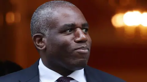 David Lammy, UK justice secretary, dressed in a suit and tie, looking to the right.