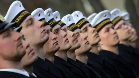 Young men in German military uniforms with white caps in Berlin.