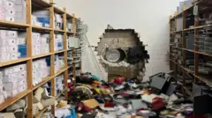 Hole drilled through Sparkasse vault wall with scattered safe deposit boxes on the floor