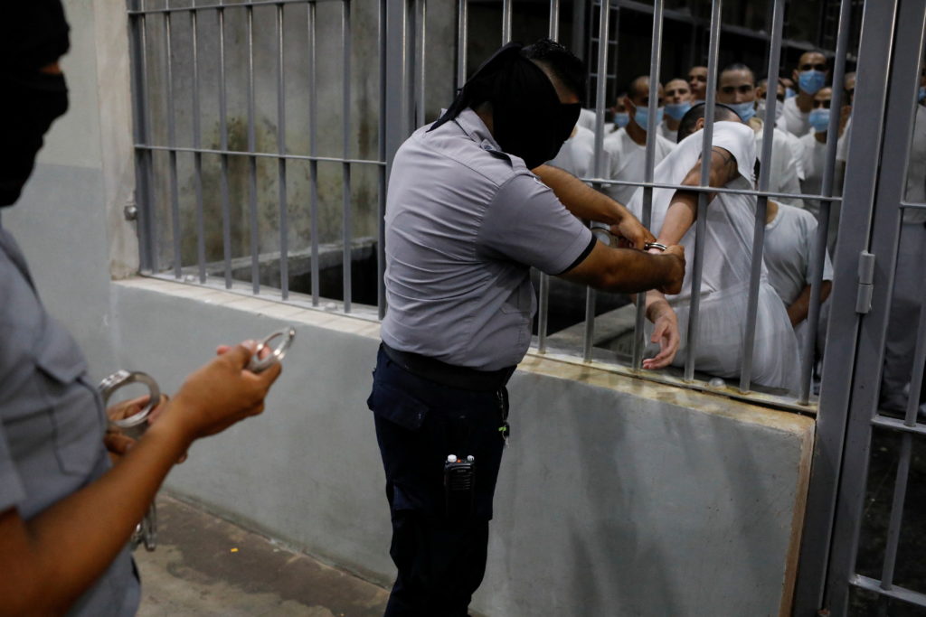A prison guard handcuffs an inmate during a media tour at El Salvador's CECOT prison in Tecoluca on April 4, 2025.