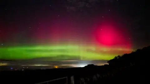 Beams of green and pink aurora lighting the sky over Haddington, East Lothian, Scotland