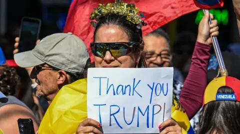 Woman holding a sign thanking Donald Trump amid celebrations in Doral after reports of Nicolas Maduro's ouster.
