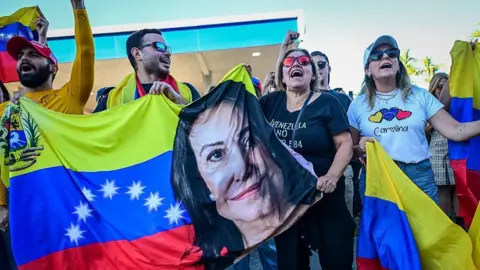 Venezuelans in Doral holding a banner with Maria Corina Machado's face at a rally on 3 January 2026.