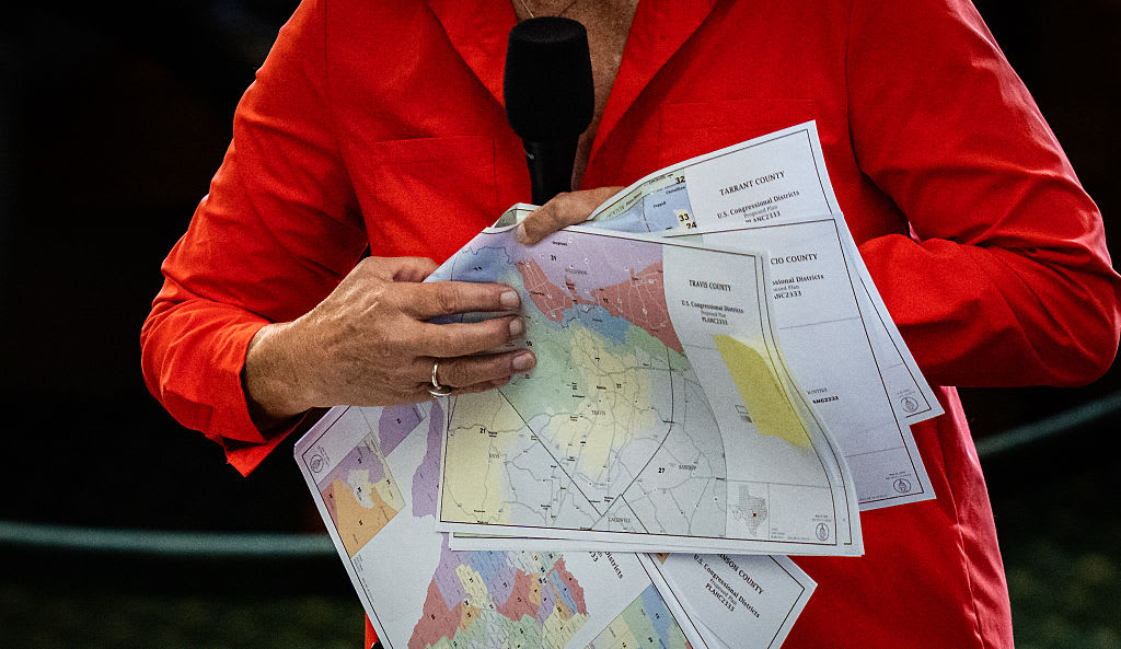 A person holds redistricting maps beside a microphone during a public hearing.