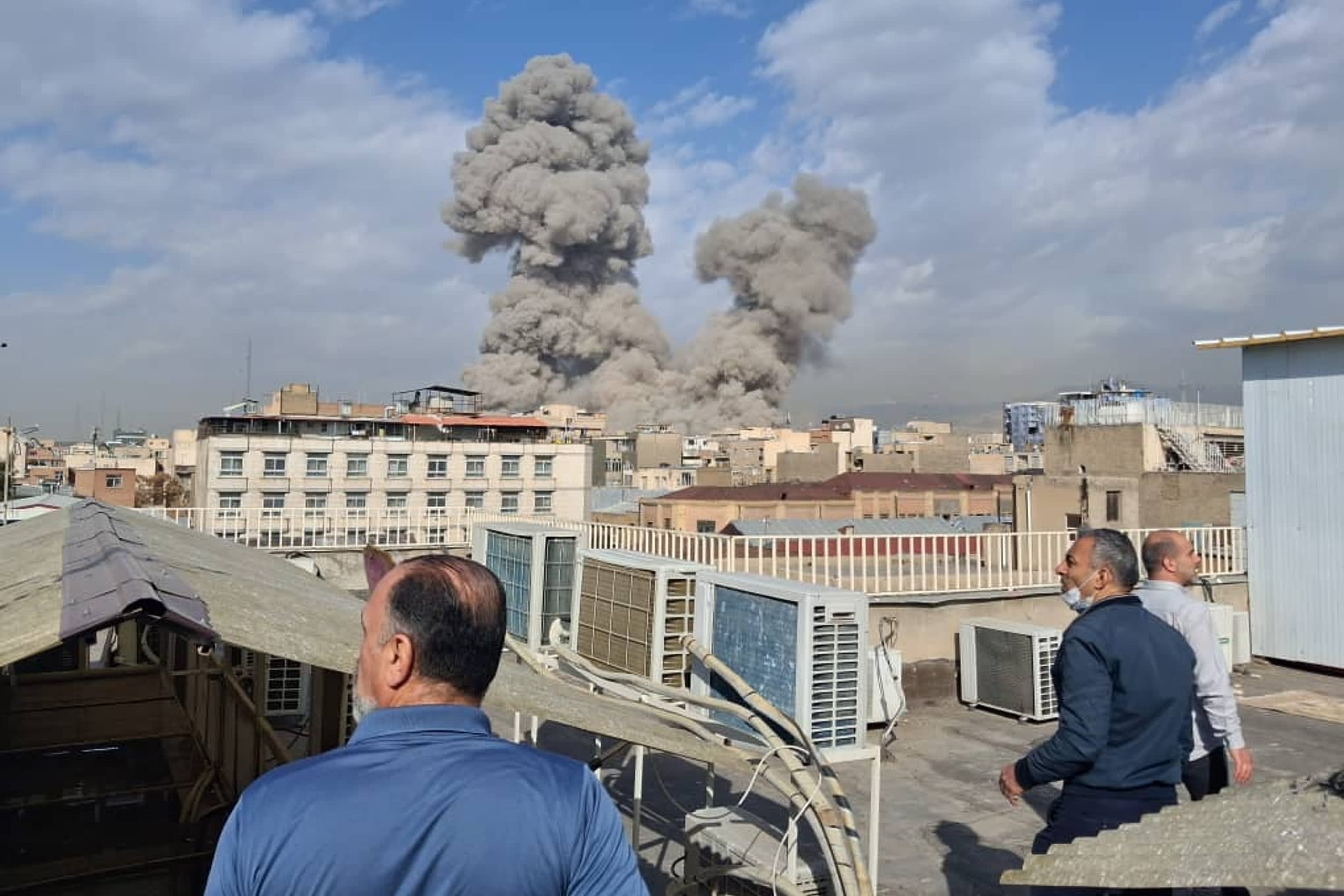Smoke plume rises over a city as residents watch amid regional strikes in early June 2026.